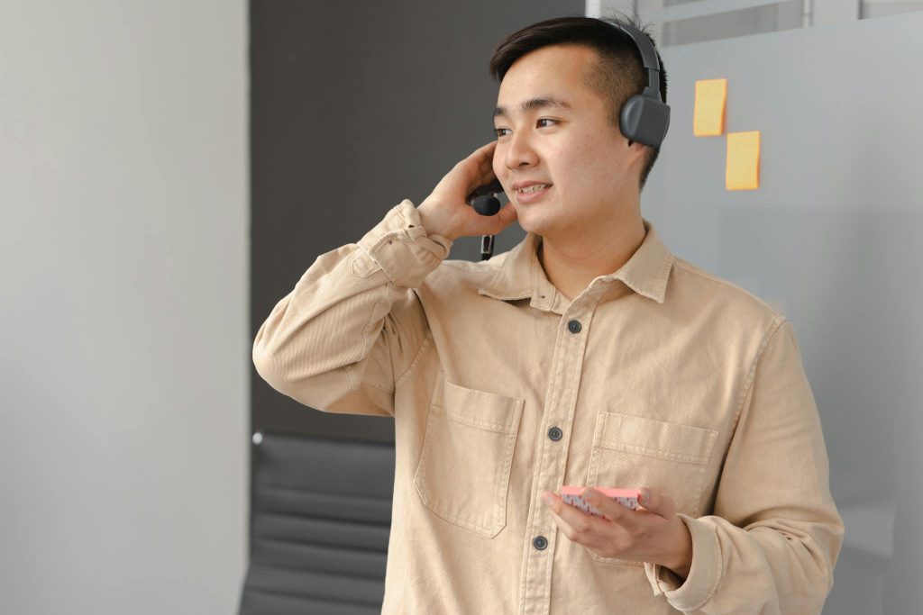 Asian man in office wearing a headset, engaged in a business call.